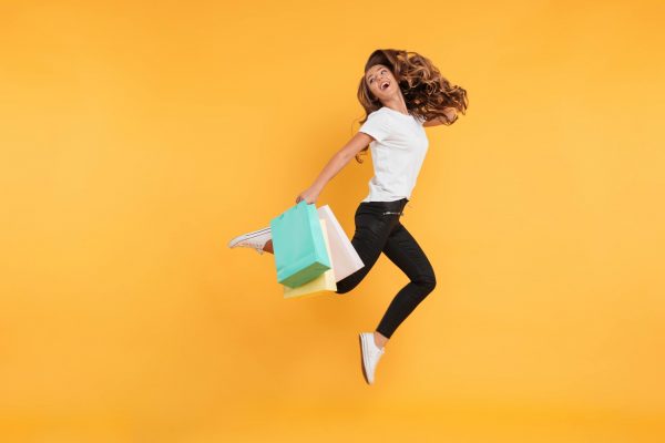 laughing-pretty-young-woman-jumping-holding-shopping-bags (1)