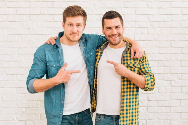 smiling-young-men-with-their-arms-around-pointing-fingers-each-other (1)